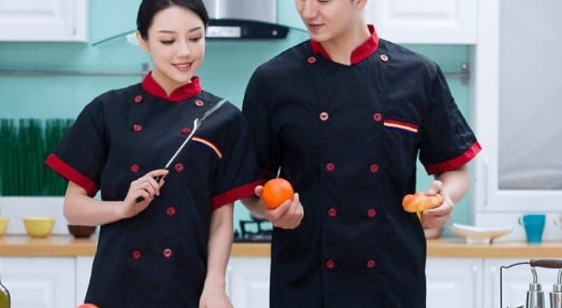 Cổ áo, nút và chần tay áo bằng màu đỏ tạo sự hài hòa cho màu xanh đen của áo đầu bếp